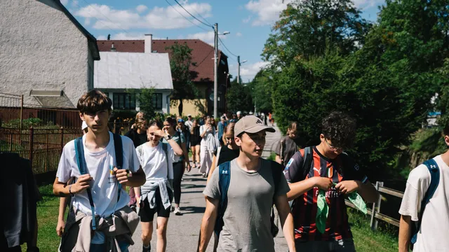 Účastníci s ruksakmi na výlete cez dedinu