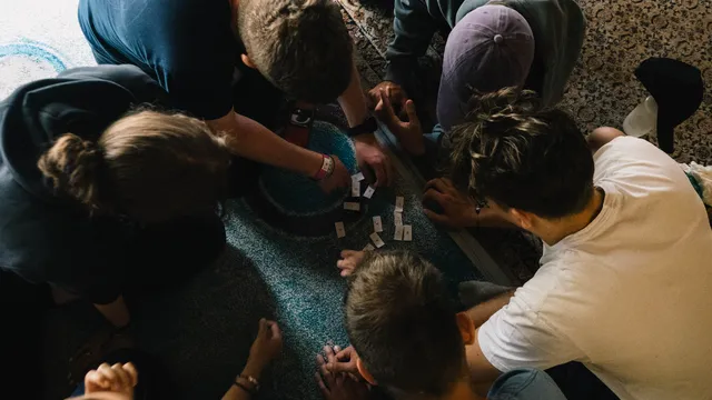 Účastníci sa skláňajú nad hracou plochou pri tímovej hre