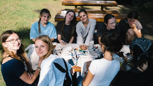 Usmiate účastníčky pri stole na lúke počas tvorivej dielne