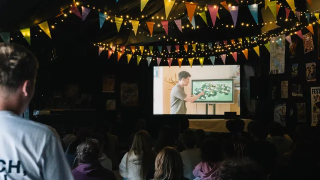 Účastníci sledujú premietanie na plátne vo vyzdobenej sále